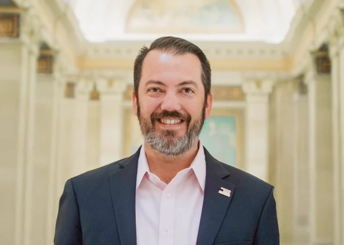 Portrait of man in a suit smiling at the camera in the Oklahoma State Capitol building.