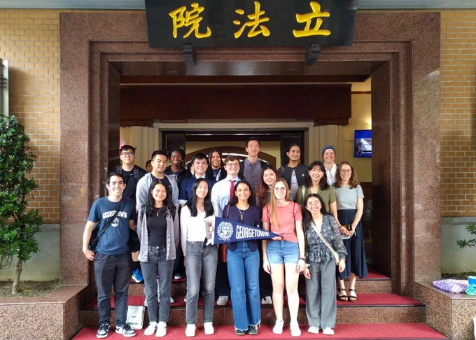 Group of students posing with a Georgetown University banner in front of the entrance to the Legislative Yuan.