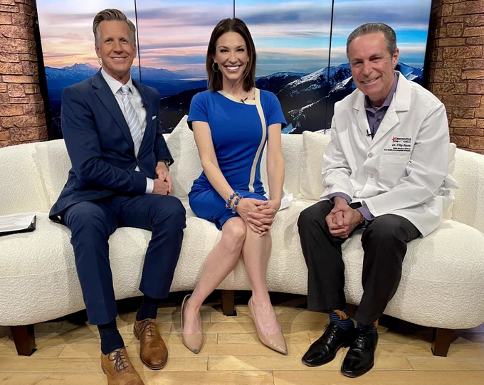 FOX13 Good Day Utah anchors, Dan Evans and Kelly Chapman, sit next to MountainStar Healthcare Chief Medical Officer, Dr. Filip Roos, on set, smiling.