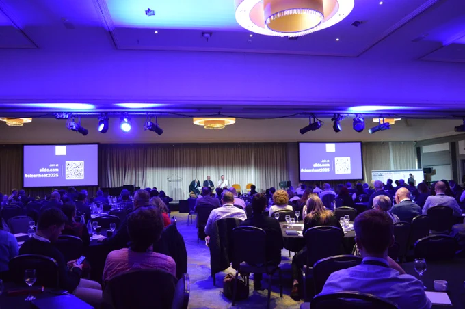 Image of the conference room full of people listening to a panel discussion on stage