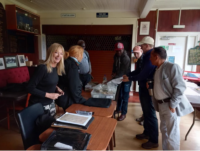 A group of refugees and people seeking asylum gathered around a table and handling some archaeological artefacts at a taster session in Glasgow.