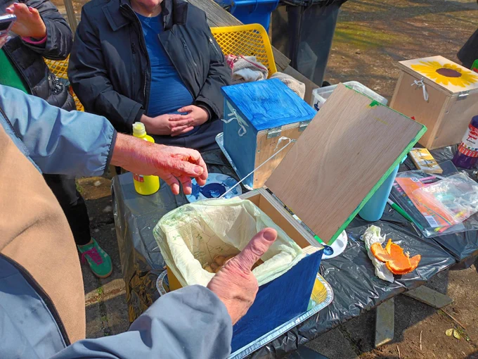 Individual giving the thumbs up in front of his wooden composting box with a food waste bag in it.