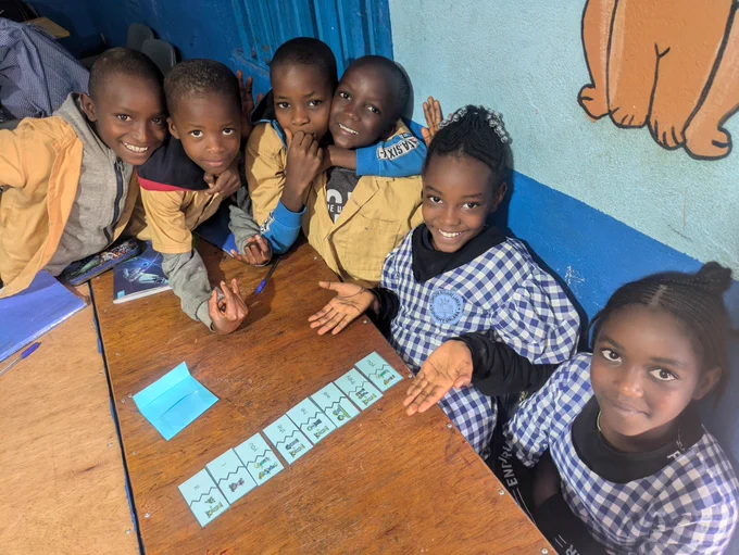 6 students sit around a table with blue flashcards on top of the table. 