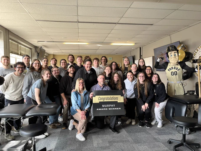 A group of students in a classroom setting, one is holding a sign