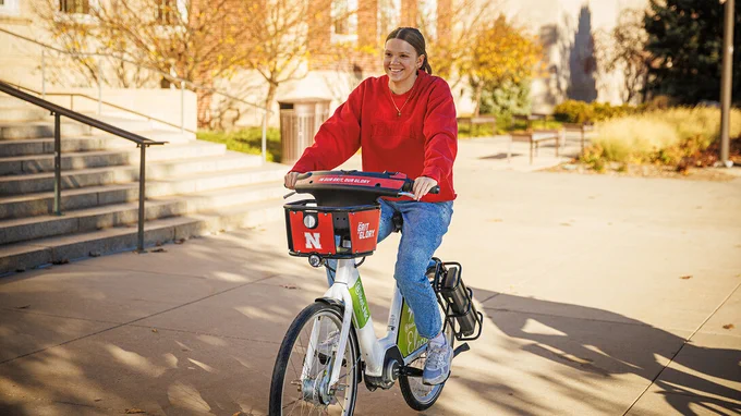 A female student rides a BikeLNK rental bicycle along R Street by the Nebraska Union. (Kristen Labadie/University Communication and Marketing)