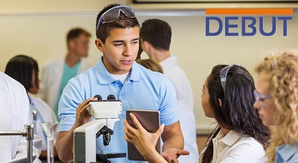 A photo of two students talking to each other in a lab setting. Overlaid text at the top right reads: DEBUT