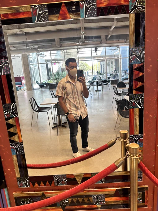mirror selfie of the cutie pie guy from the previous photo, where a detailed art display houses the mirror, and is blocked by red velvet ropes