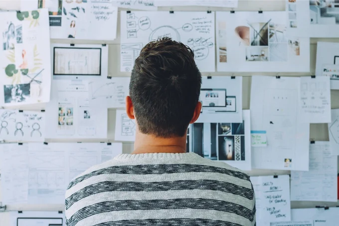 Photo of someone looking at a whiteboard covered in paper with ideas on