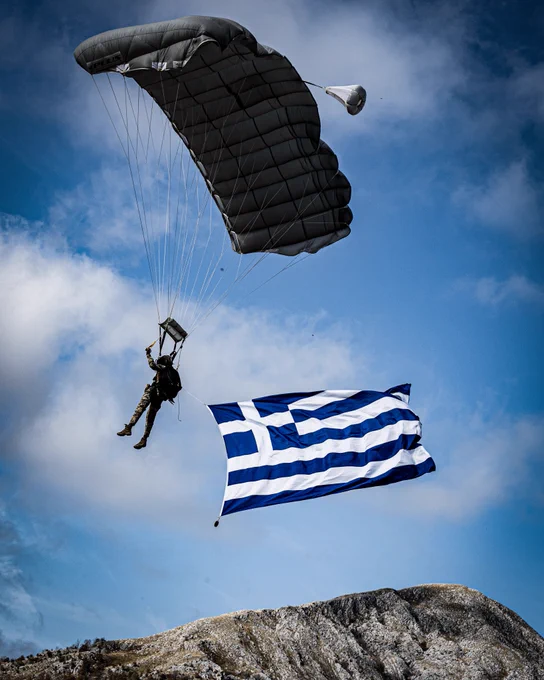 A Greek Special Forces operator displays the Greek flag during a parachute drop into a training area high in the Albanian mountains. 
