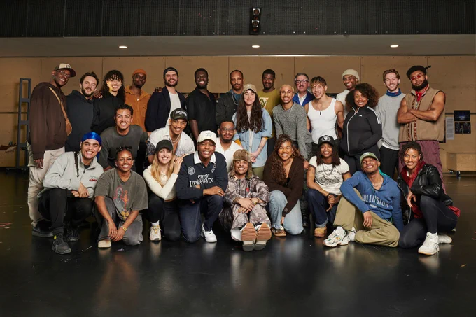 A cast of actors gathered together to pose for a group photo