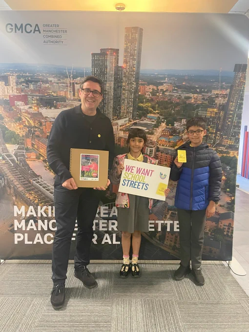 Andy Burnham with two children holidng our, Our Manchester Our Air photo scarpbook.
