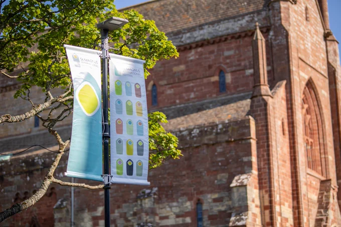 Image of St Magnus International Festival banners hanging on Broad Street in Kirkwall, with St Magnus Cathedral behind.