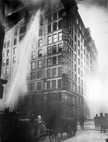 Firefighters attempt to extinguish a blaze on the high floors of the Asch Building in New York City after a fire ignited in the Triangle Shirtwaist Company factory on March 25, 1911. The fire department's ladders did not reach the uppermost floors. Photo courtesy of the Kheel Center at Cornell University.