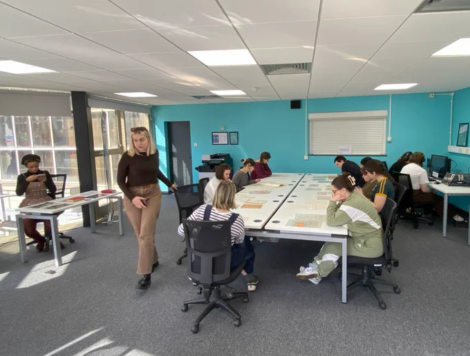 Staff and students in the reading room sat around a table studying documents