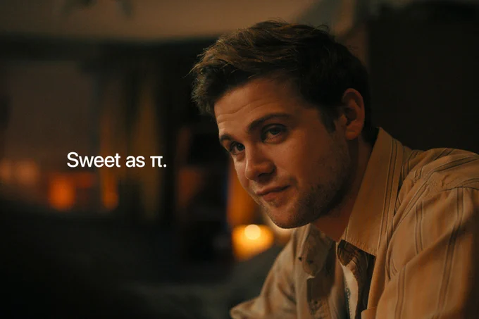 From Prime Target. Edward Brooks, portrayed by Leo Woodall, looks at someone earnestly in warm lighting. There is text to the left of him that reads: "Sweet as Π."