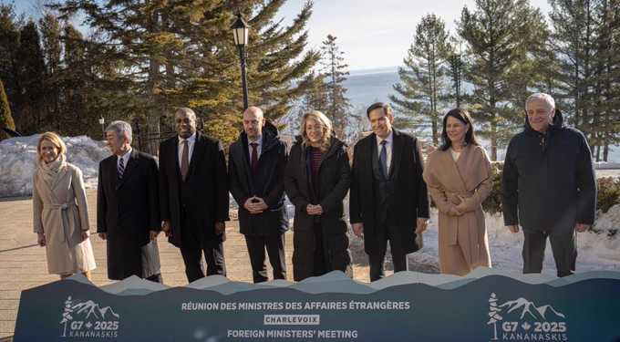 Secretary Rubio stands outdoors in a line with other foreign ministers posing for a group photograph. They stand behind a long sign low to the ground that displays G7 2025 Kananaskis, the meeting emblem, Charlevoix, and Foreign Ministers’ Meeting in English and French. (State Department/Freddie Everett)