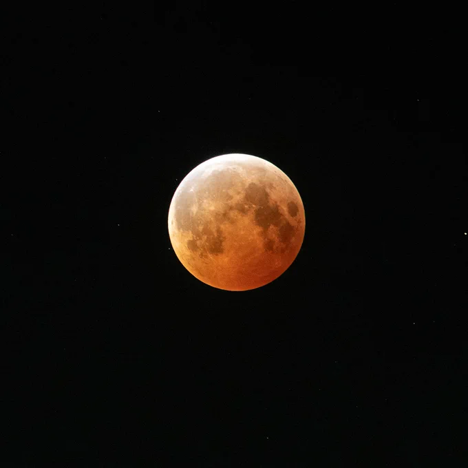 The lunar eclipse as seen above the Space Environments Complex at NASA’s Glenn Research Center at Neil Armstrong Test Facility in Sandusky, Ohio, during the early hours of March 14, 2025. A white to orange to red gradient sweeps across the Moon from the top left to the bottom right of its full disc. Credit: NASA/Sara Lowthian-Hanna