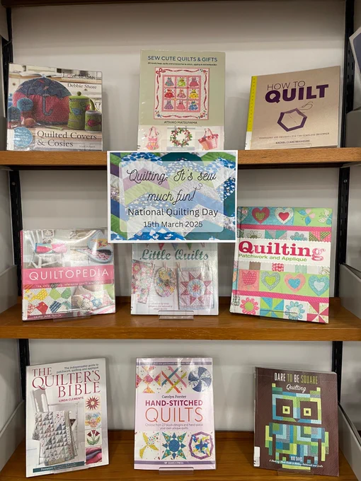 A display of library books about quilting, with a sign which reads "Quilting is sew much fun."