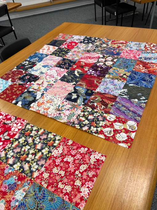 Squares of fabric sewn into a square grid, in an array of colours and patterns, including butterflies, flowers, birds and waves.