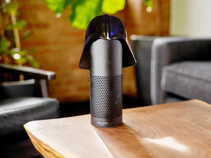 A cylindrical black Alexa speaker on a coffee table; it is wearing a Darth Vader helmet.

Image:
Stock Catalog/https://www.quotecatalog.com (modified)
https://commons.wikimedia.org/wiki/File:Alexa_(40770465691).jpg

Sam Howzit (modified)
https://commons.wikimedia.org/wiki/File:SWC_6_-_Darth_Vader_Costume_(7865106344).jpg

CC BY 2.0
https://creativecommons.org/licenses/by/2.0/deed.en