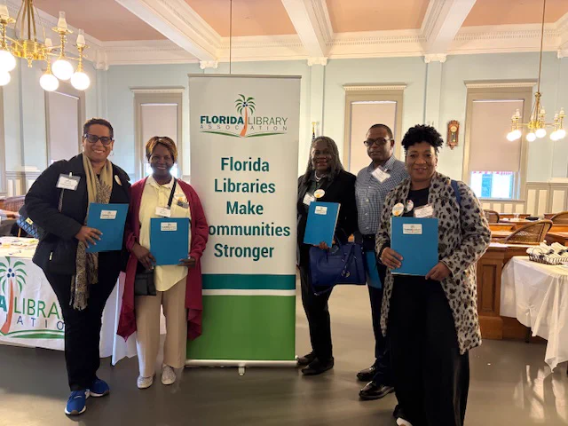 Photo of advocates and members next to the Florida Libraries Make Communities Stronger sign