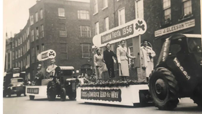Black and white photo of St Patrick's Day floats being pulled by tractors in the 1950s