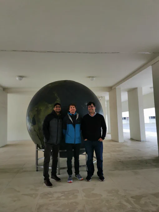 Viren, Arno, and Tiago in front of a globe (world)