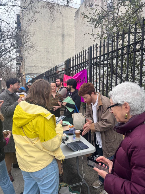 Photo of a crowd of people around a folding table getting checked in for volunteer shifts.