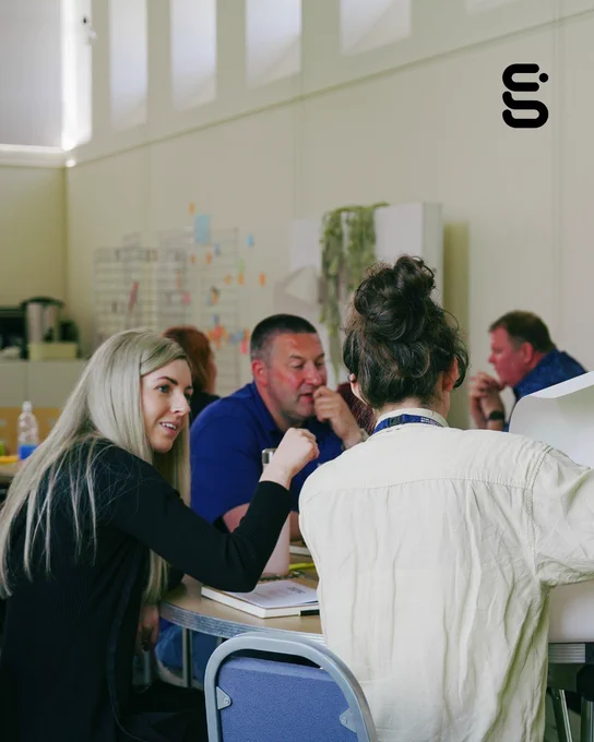 A group of people engaged in an activity around a table.