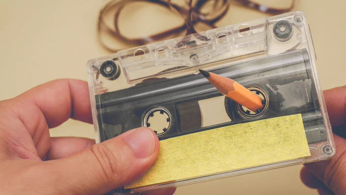 person winds loose tape to fix a cassette tape