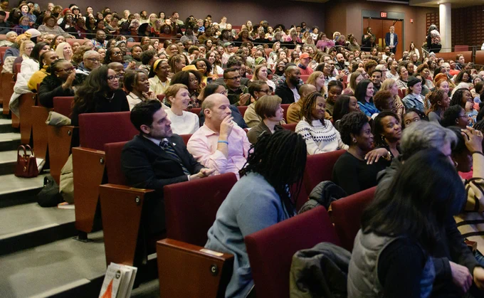 The audience at the Isabel Bader Theatre listens attentively to Chimamanda Ngozi Adichie, their faces reflecting interest and engagement.
