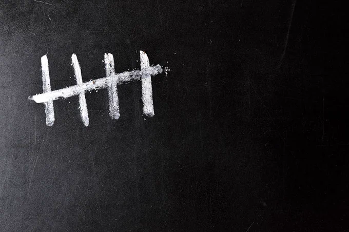 Five chalk tally marks on a black chalkboard background.