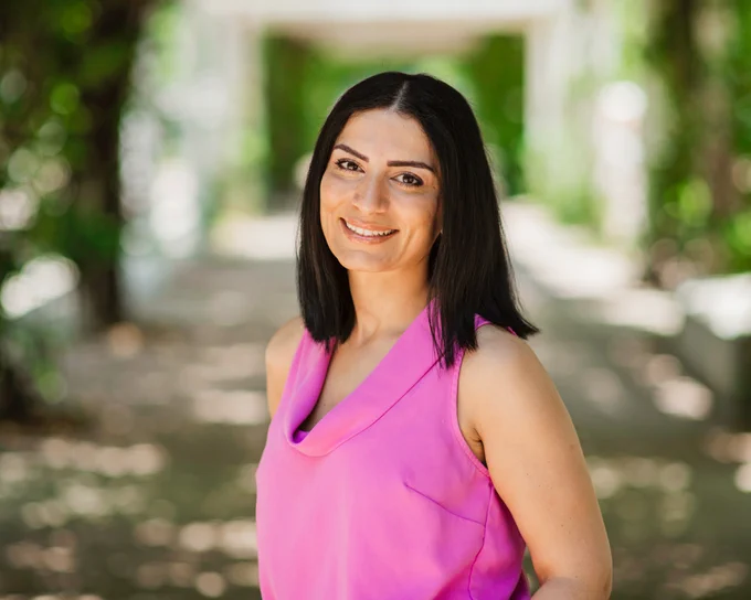 Portrait of woman smiling at the camera in an outdoors setting.