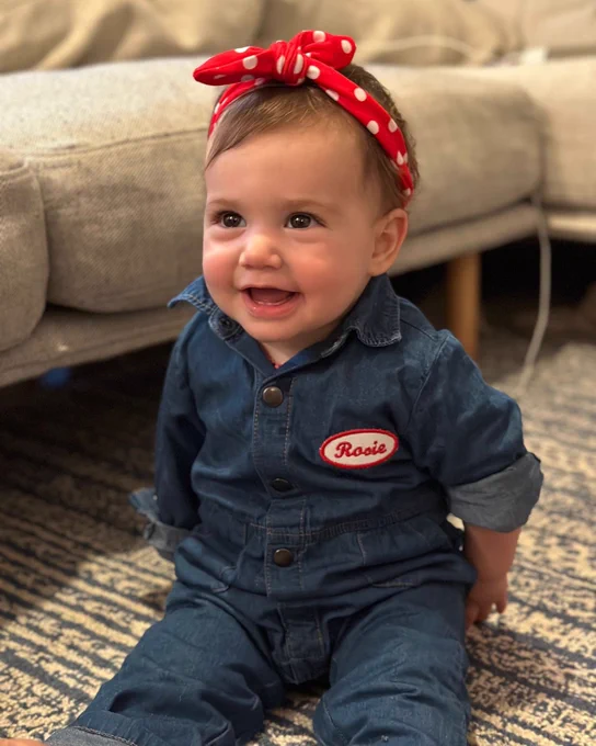 Photo of Rosie—a UAW member’s daughter—dressed in a Rosie the Riveter costume for Halloween. She is sitting and smiling.