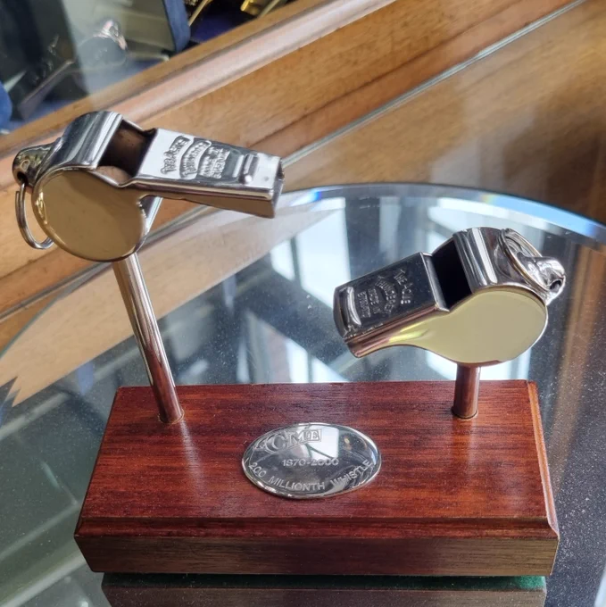 Two silver whistles made by ACME Whistles.