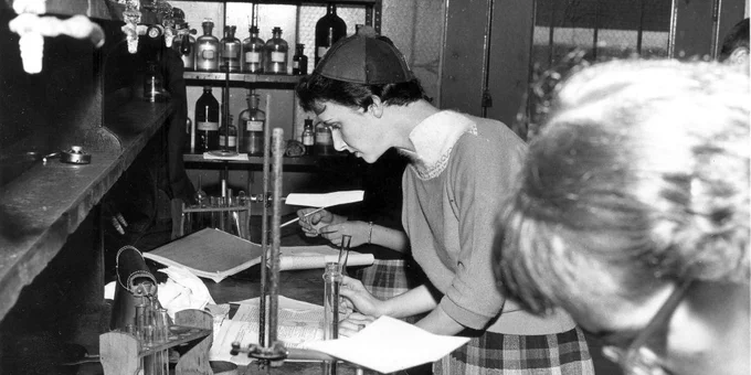 Black and white photo from the Duquesne University Archives. Photo shows two women in a Duquesne science class working at a lab table.