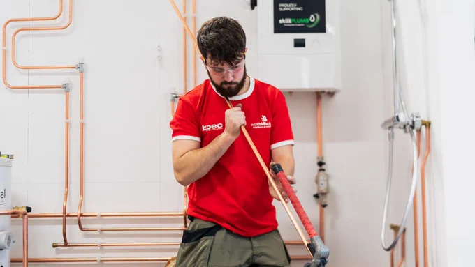 Plumber in red tshirt with pipework