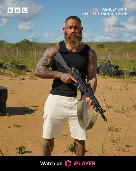 Ashley Cain holding a large gun.