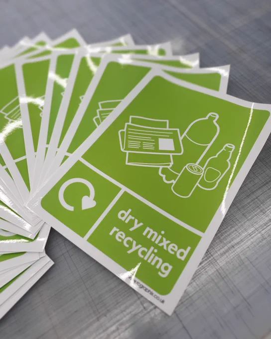 Pile of 'dry mixed recycling' stickers on a workbench.
