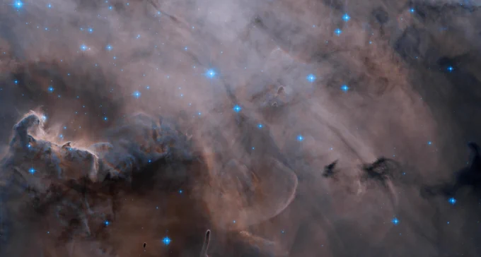 A roiling region of dark dust and gas fills the image, interspersed with glowing blue stars. Credit: NASA, ESA, M. Mutchler (Space Telescope Science Institute); Processing: Gladys Kober (NASA/Catholic University of America