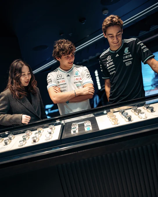 George Russell and Kimi Antonelli are shown a display of IWC watches by a member of the IWC team.