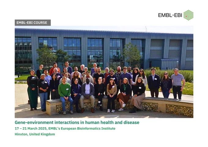 A group of around 30 people are sitting on a bench or standing behind the bench outside. A large grey building is visible in the background. The group are smiling at the camera.
The text reads:
Gene-environment interactions in human health and disease 
17 - 21 March 2025, EMBL's European Bioinformatics Institute
Hinxton, United Kingdom 