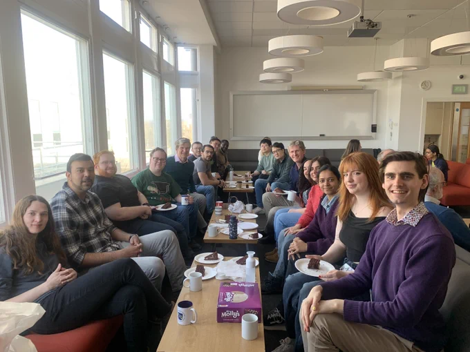 The group having coffee and cake together to celebrate David completing his viva.