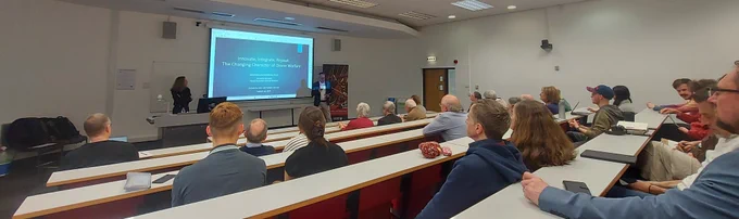 A lecture room with an audience watching Dominika Kunertova, introduced by Marco Wyss