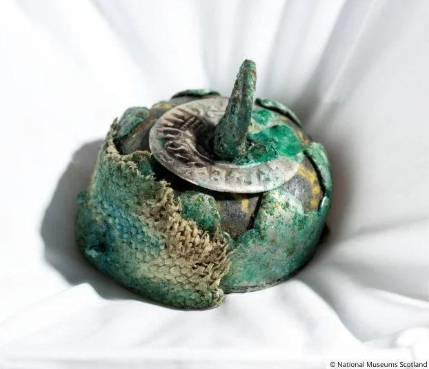 Photo of a small bead with a hook on top with textile wrapped around it