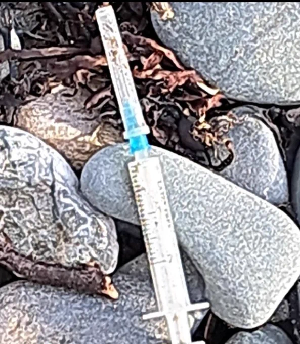 Syringe with plastic cap lying between the rocks