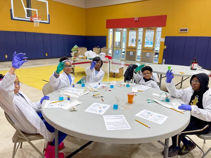 Group of K-12 students around a table taking part in a science experiment
