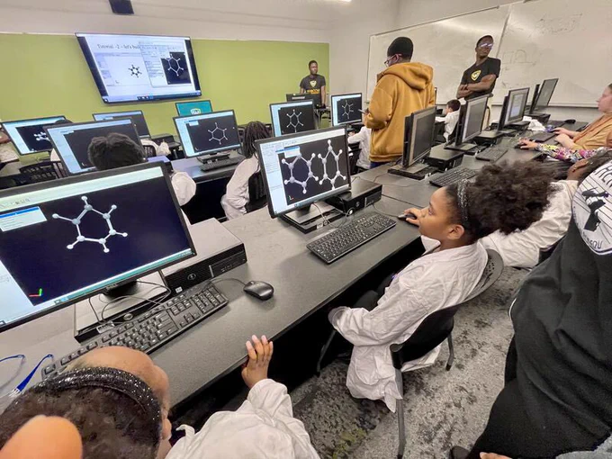 Group of K-12 students sitting at computers learning about computational chemistry