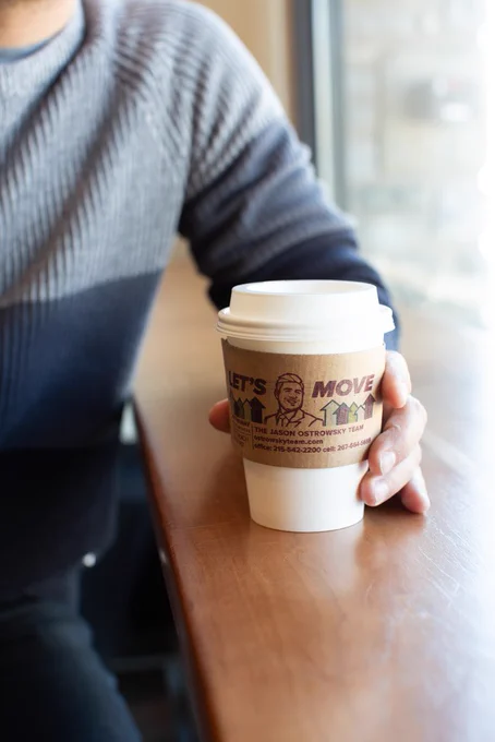 Image of to-go coffee cup with advertisement on coffee sleeve.