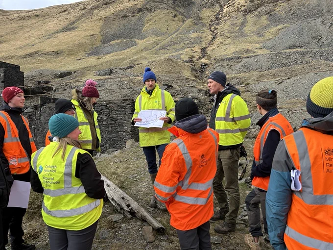 Colleagues listening to a talk at Cwmystwyth metal mine with the spoil tips in the background